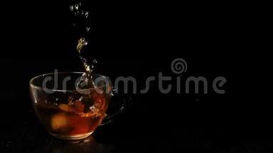 茶道。 红茶叶子在透明的茶壶里漂浮和旋转。茶道。 两个冰块掉进透明的杯子里